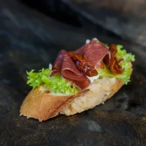 Брускетта з хамоном, в'яленим томатом і листям салату